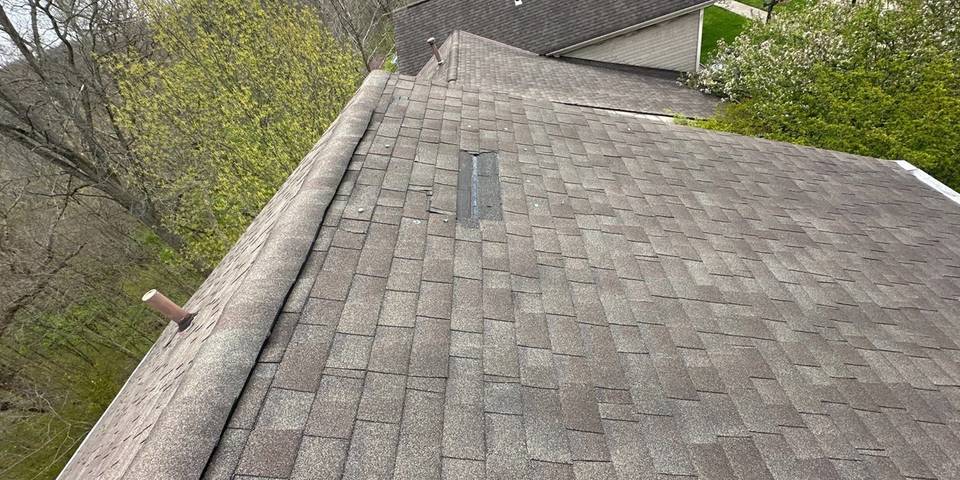 A missing strip of shingles near the top of the roof after the wind.