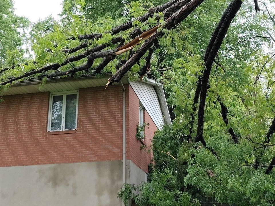 A tree limb resting across the roof edge of a brick home in Beavercreek, Ohio.