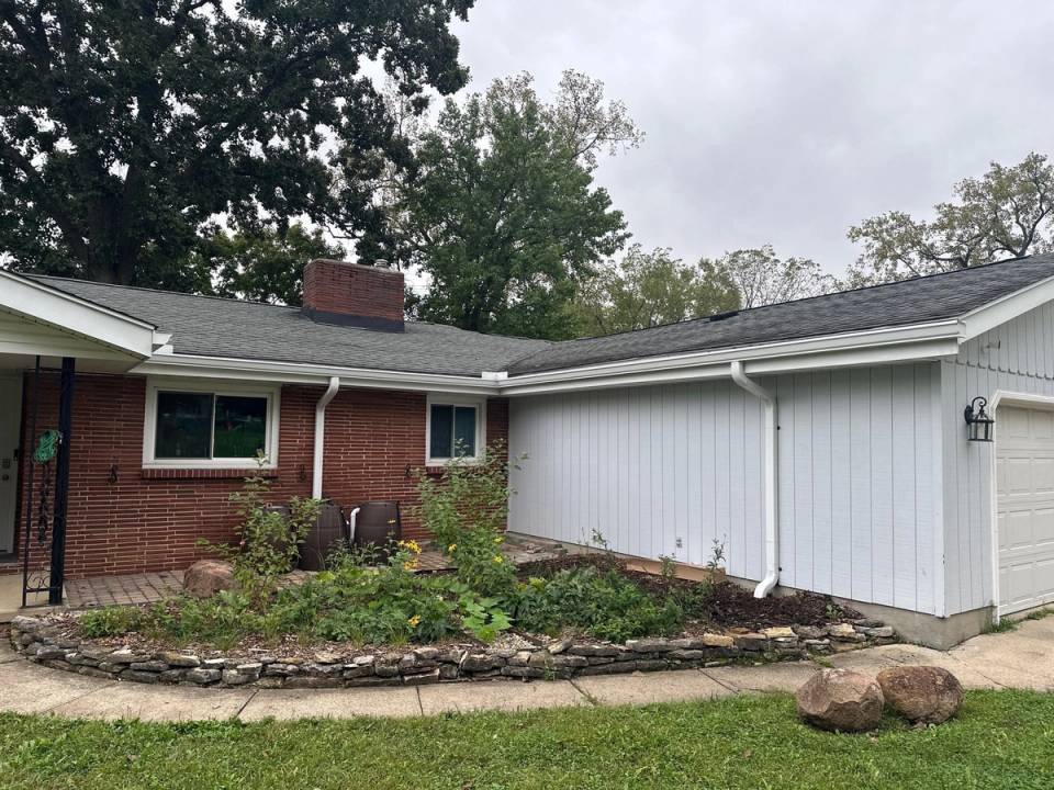 New white seamless gutters and downspouts on a brick and white-sided ranch in Dayton, Ohio.
