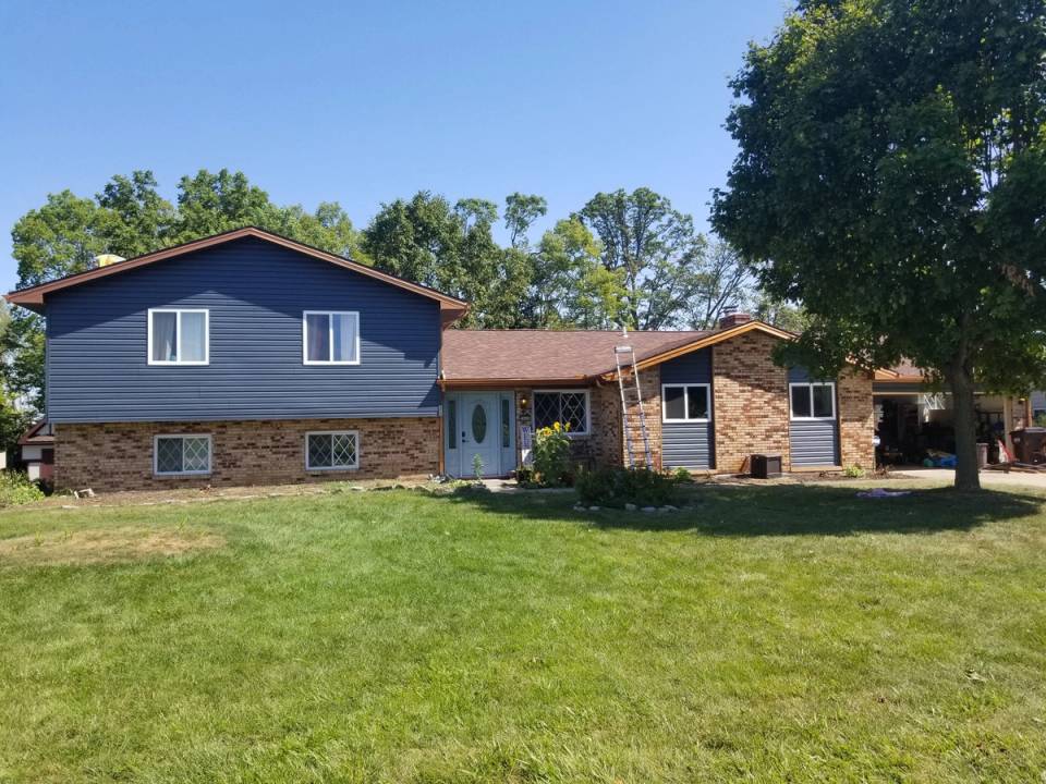 The finished house from the front lawn in dark blue-gray siding with copper-colored trim, Beavercreek, Ohio.