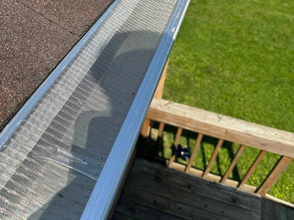 A stainless mesh gutter guard along the eave of a Kettering, Ohio home, with the deck and lawn below.